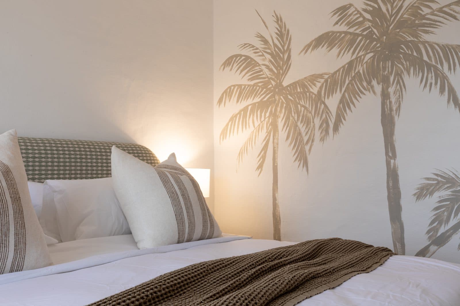 Hand-painted palm mural above the bed